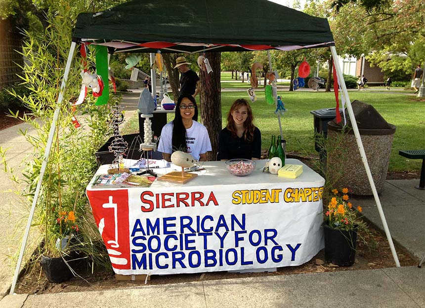 Two Sierra Student ASM members sitting behind display table on campus.